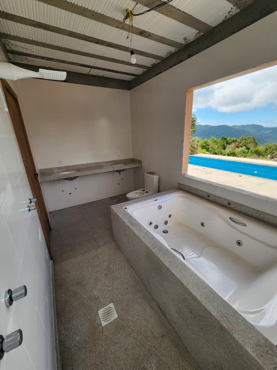 Banheira de hidromassagem com borda em granito e vista para a piscina