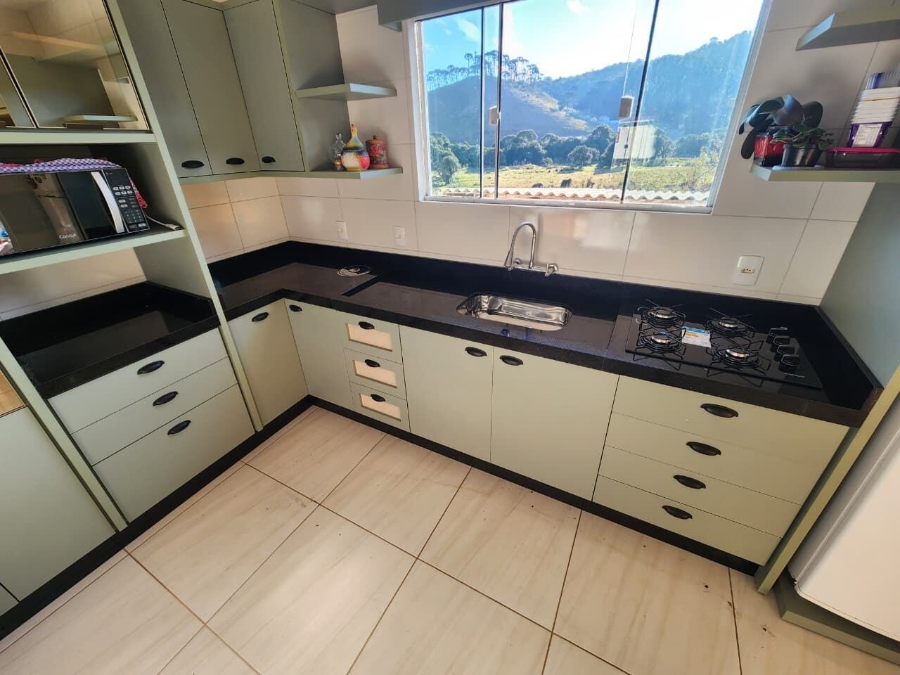 Cozinha planejada com bancada preta e armários verde oliva