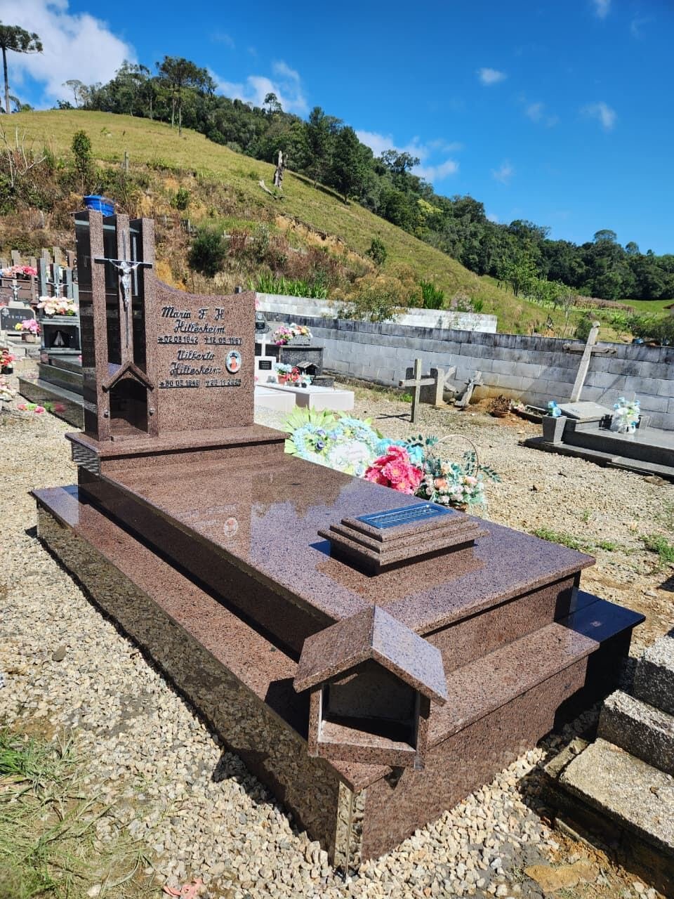 Túmulo em granito rosa com cruz e placa de homenagem